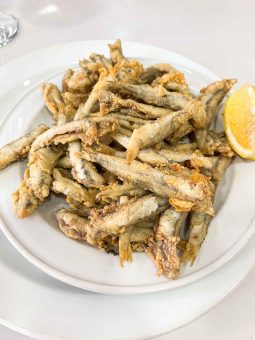 Boquerones fritos — a pile of whole battered fried anchovies with a lemon wedge on a white plate at Los Marianos, Granada