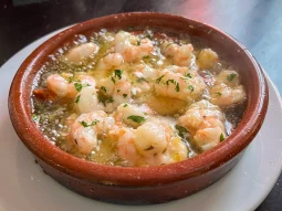 Gambas al ajillo — peeled prawns bubbling in garlic olive oil with chopped parsley in a clay cazuela at Los Marianos, Granada