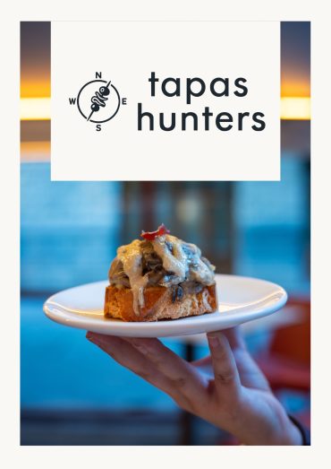 Tapas Hunters Issue 01 cover — logo over a pintxo de hongos con jamón held on a white plate at El Globo, Bilbao