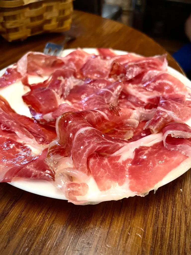 Jamón ibérico — thin hand-cut slices with marbled fat glistening on a white plate at La Cepa, San Sebastián