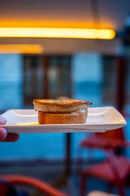 Pintxo de foie a la plancha — seared foie gras on toasted bread held on a white rectangular plate at El Globo, Bilbao