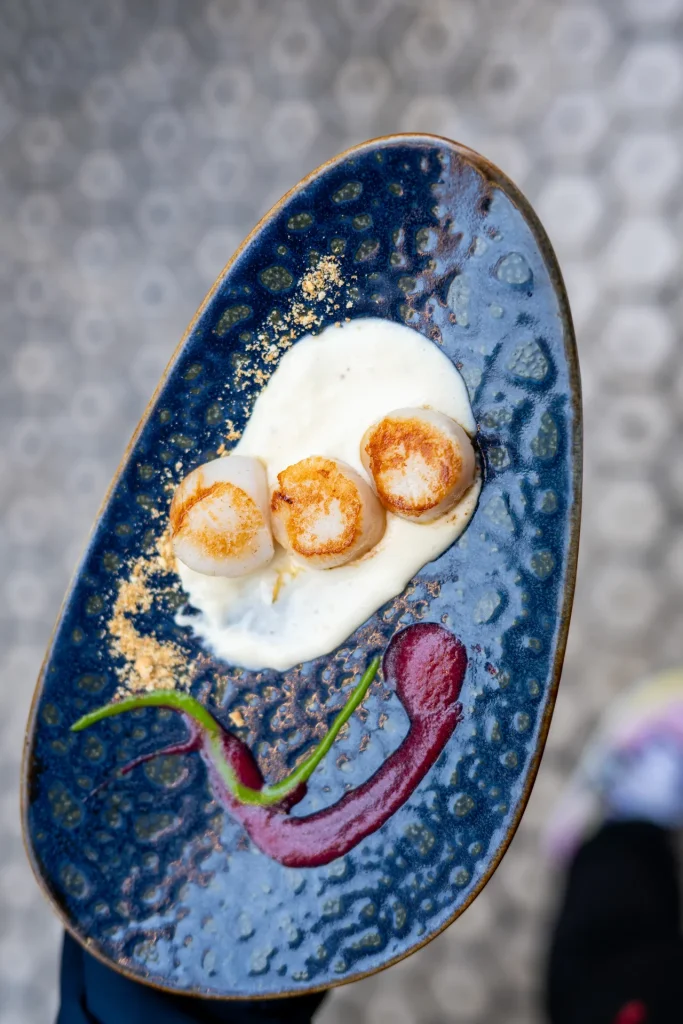 Vieiras a la plancha con puré trufado — three seared scallops on truffle cream with red sauce and crumble on a blue ceramic plate at Bar Antonio, San Sebastián