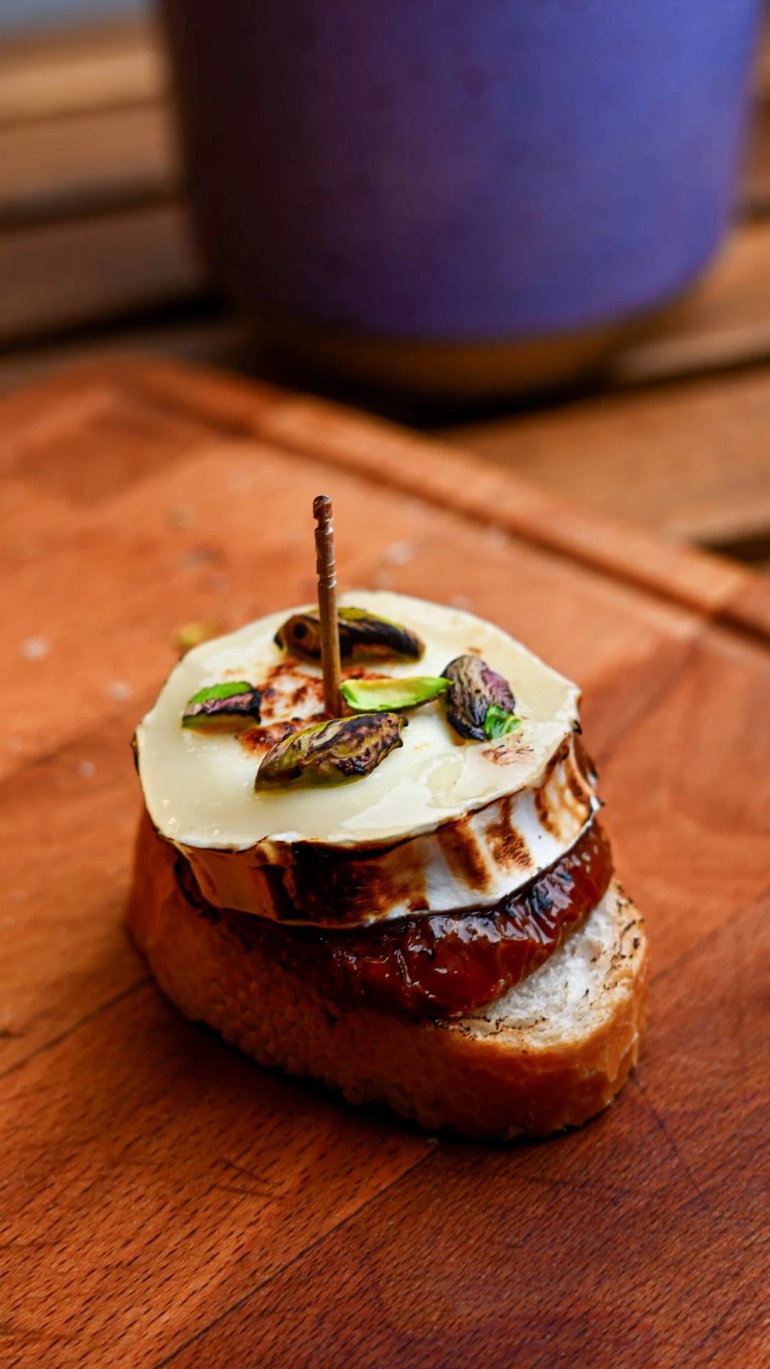 Pintxo de bonito — three baguette slices topped with tuna spread, roasted red pepper and anchovy, skewered with olives on a wooden board, Basque Country