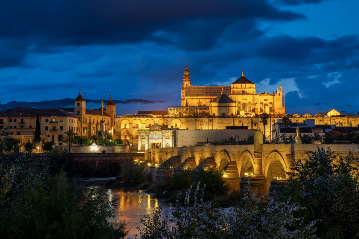 Mezquita-Catedral and Roman Bridge illuminated at night over the Guadalquivir river, Córdoba, Spain
