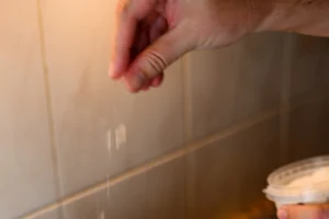 Mejillones al vapor step 3 — a hand pinching salt and dropping it, with a salt container visible in the bottom right corner