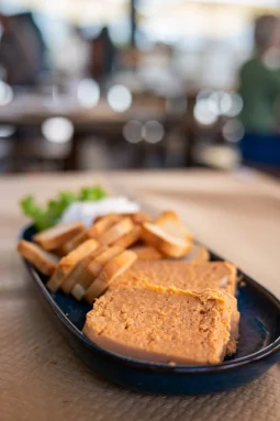 Pastel de cabracho - a dense orange fish pâté wedge with toasted bread slices on a dark oval plate at Sidrería La Casona, Llanes