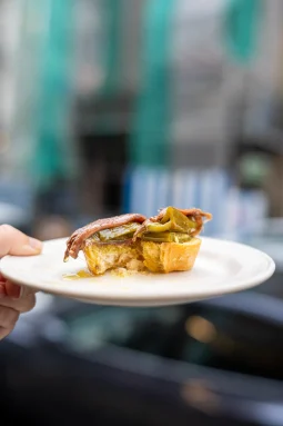 Pintxo de antxoa — anchovy fillet and green pepper on an oil-soaked baguette slice held on a white plate at Antonio Bar, San Sebastián