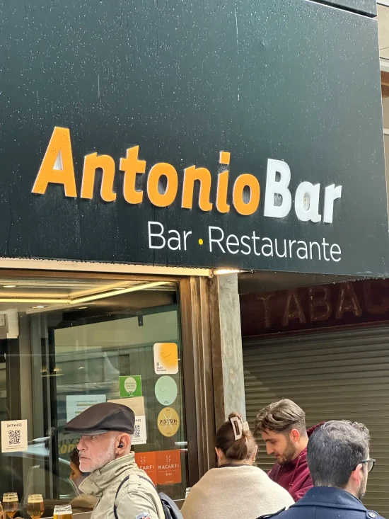 Antonio Bar sign above a busy pavement entrance with people eating outside, San Sebastián, Spain
