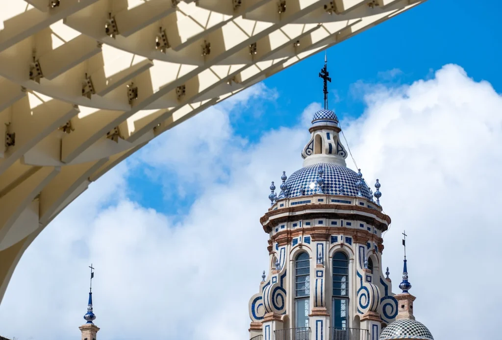 Plaza de España tiled dome framed by Las Setas wooden canopy against a blue sky, Sevilla, Spain