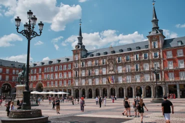 Madrid Plaza Mayor — frescoed Casa de la Panadería facade, equestrian statue and ornate lamp post, crowds on the cobbled square