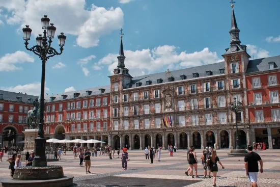 Madrid Plaza Mayor — frescoed Casa de la Panadería facade, equestrian statue and ornate lamp post, crowds on the cobbled square