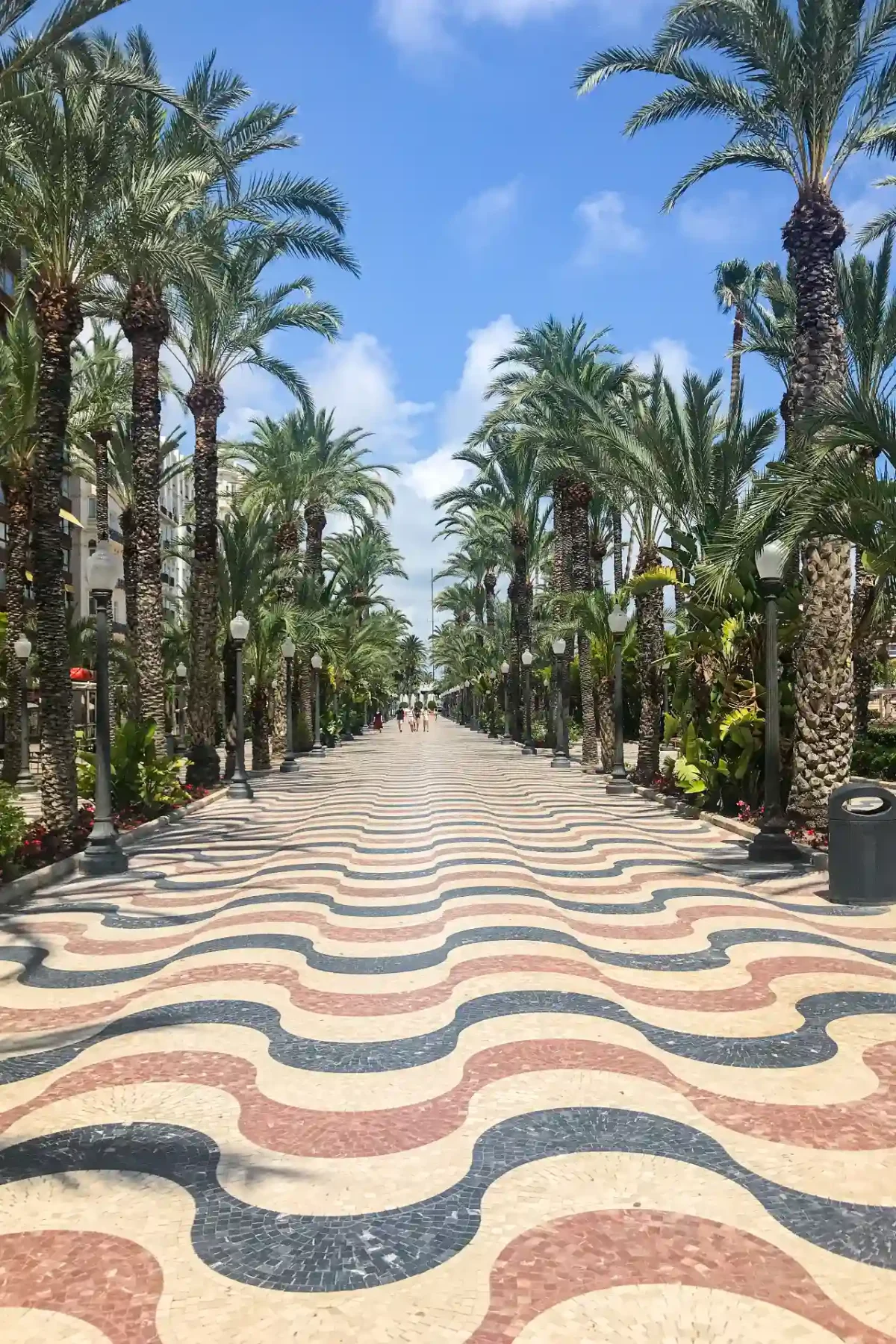 Alicante Explanada de España — wide palm-lined promenade with a bold wave-pattern mosaic floor in cream, terracotta and grey