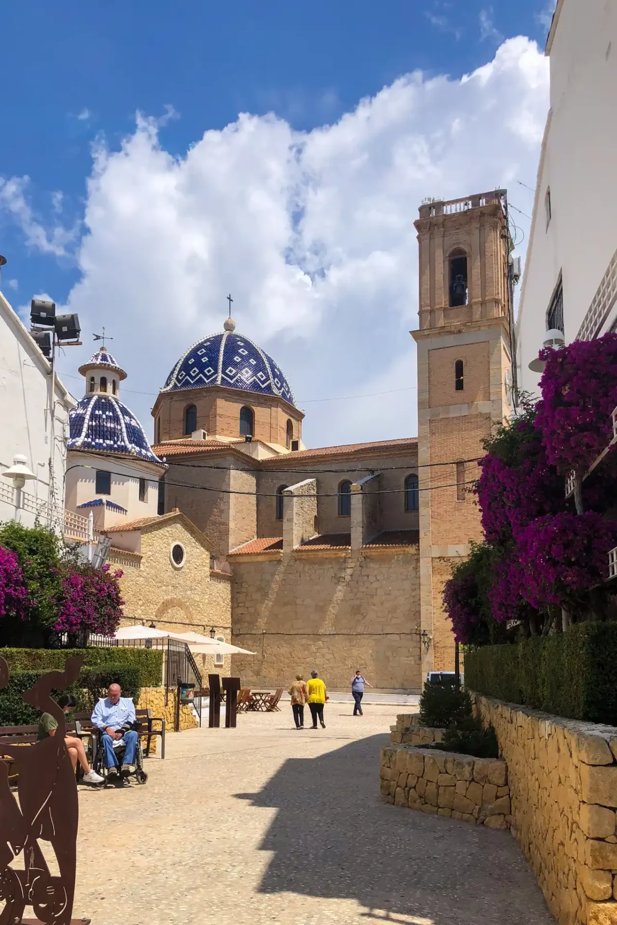 Altea old town plaza — church with a blue and white tiled dome and square bell tower, framed by purple bougainvillea, Alicante