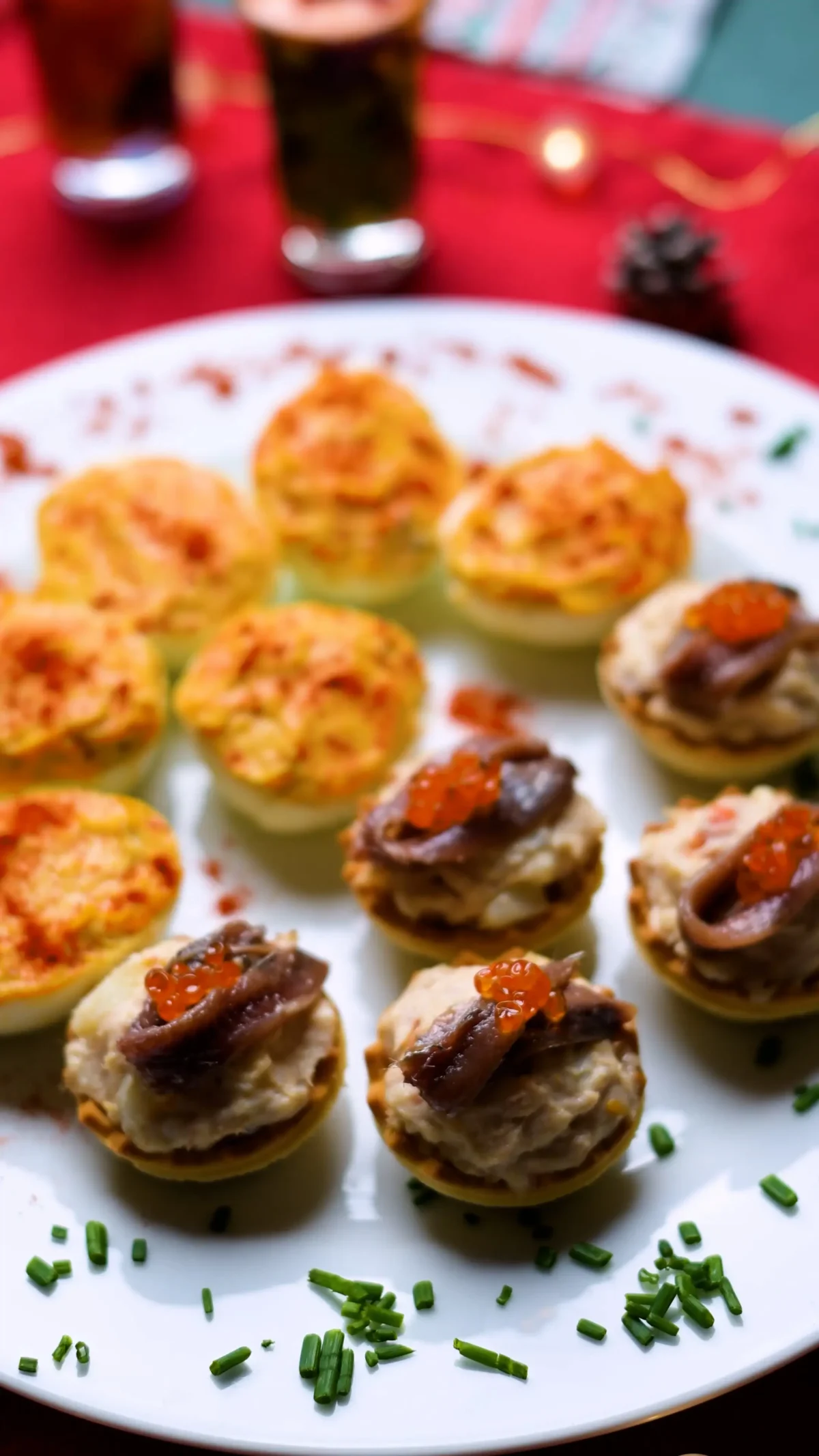 Canapés de ensaladilla rusa — mini pastry cups filled with Russian salad topped with anchovy and fish roe on a white plate, Spain