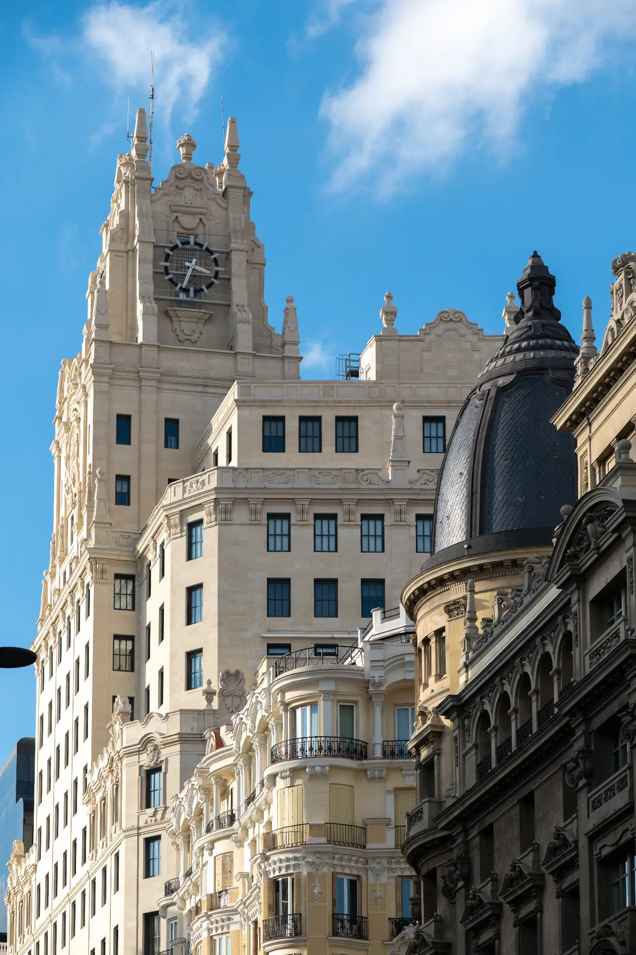 Madrid Gran Vía architecture — Telefónica building clock tower and ornate early 20th-century facades with iron balconies against a blue sky