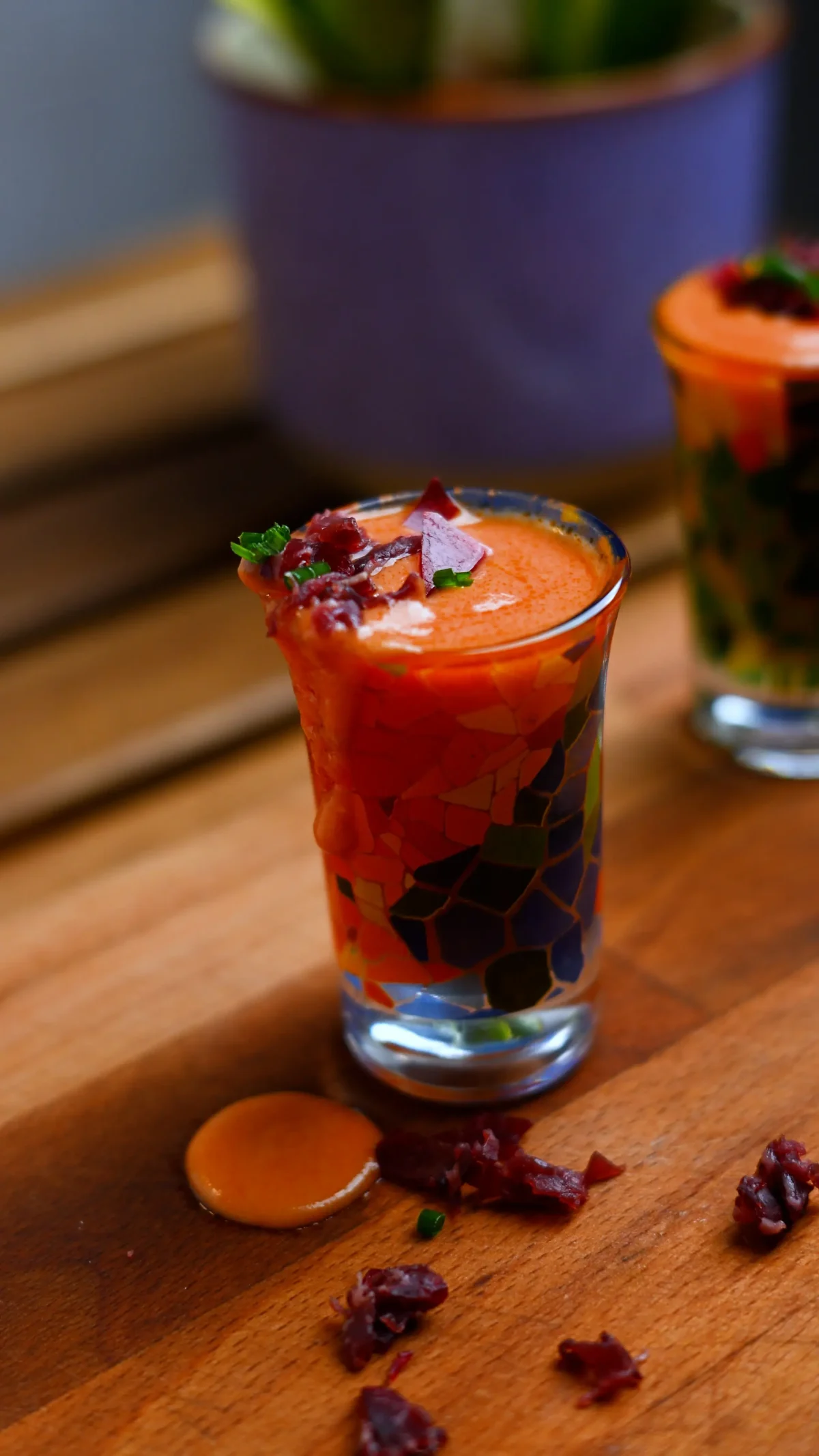 Salmorejo shots — thick chilled tomato soup in decorated shot glasses topped with jamón crumbles and chopped parsley, Spain