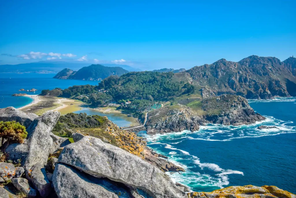 High-angle panoramic view of the rugged Cíes Islands, rocky cliffs, sandy beaches, and blue ocean near Vigo, Spain.