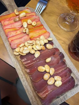Slices of cured mojama and huevas de maruca garnished with roasted almonds on a wooden serving board at La Trastienda, Granada.