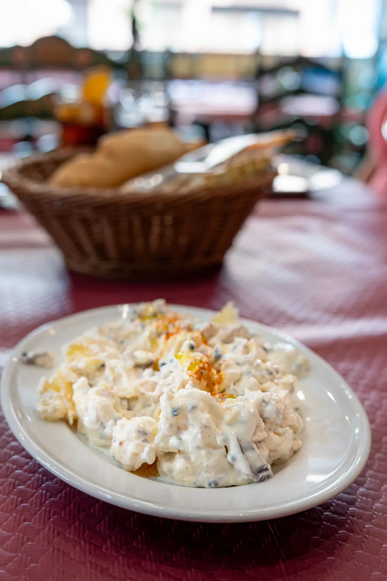 Close-up of creamy potato and octopus salad (ensaladilla de pulpo) garnished with paprika and olive oil on a white plate at Sol y Sombra in Seville, Spain