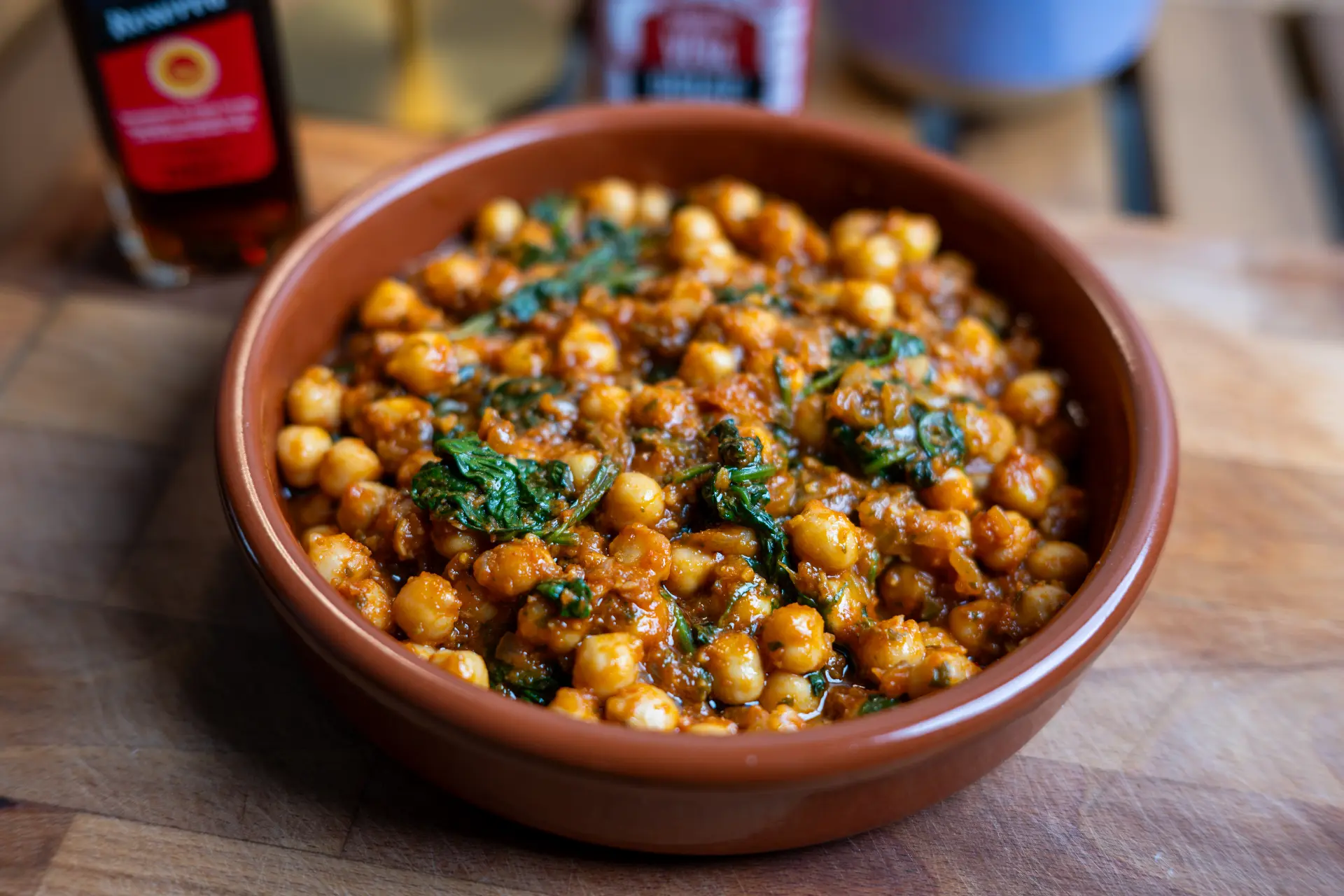 Cover image featuring a terracotta bowl filled with traditional Spanish chickpea and spinach stew (garbanzos con espinacas), garnished with spices and sherry vinegar in the background